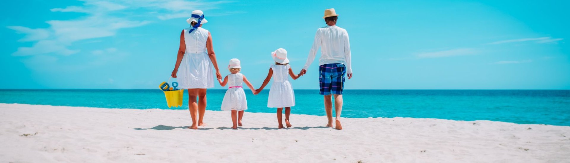 Family walking hand in hand on a white beach
